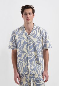 Korte mouwen overhemd in lichtblauw met een romig abstract bladerenpatroon. Voorzien van een notch-kraag en knopen, gemaakt van ademende stof.