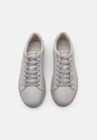 Γκρίζα δερμάτινα αθλητικά παπού�τσια με απαλή υφή, στρογγυλή μύτη και γκρίζες κορδόνες. Διαθέτουν μινιμαλιστικό σχέδιο και υφασμένο ελαστικό πάτο.