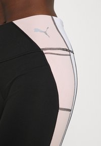 Czarno-różowe legginsy o wysokim stanie z kontrastowymi panelami, z płaskimi szwami i jasnoszarym logo Pumy po boku.