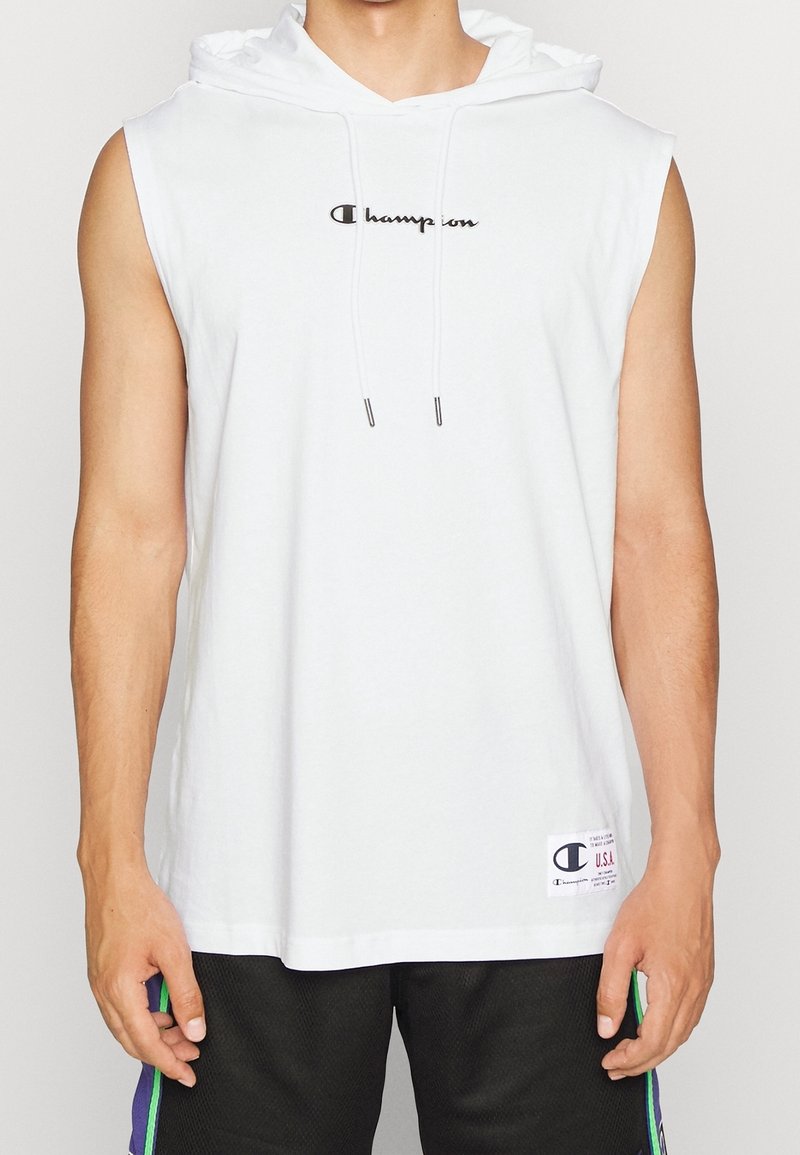 Homme portant un sweat à capuche blanc sans manches Champion avec cordons et un short noir avec des rayures vertes et violettes.