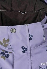 Lila tyg med mönster av blåbär och blad, med en svart innerfoder och en metallknapp med logoinskrift.