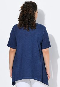 Tunikatoppi tummansinisenä, lyhythihaisena, rentoa istuvuutta, pyöristetty helma ja sivuvetoluukut. Valmistettu kevyestä, teksturoidusta kankaasta.