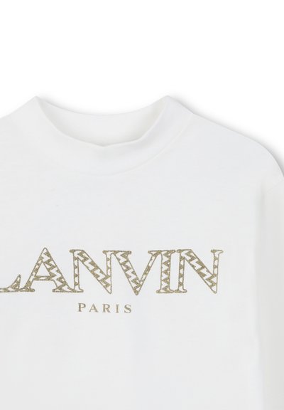 Hvit genser med ribbestrikket, rund halslinje som har et gull zigzag-mønster av logoen som leser "LANVIN PARIS" med metallisk skrift.