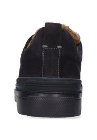 Schwarzer Wildleder-Schlüpfschuh mit tanfarbenem, flauschigem Futter, flacher schwarzer Sohle und kontrastierendem grauem Nähten auf der Rückseite. Abgerundete Schuhspitze.