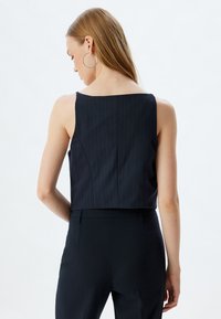 Navy sinirityyppinen hihaton crop-top, jossa on jämäkkä takaosa, suora kaula-aukko ja sileä pinta.