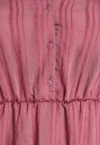 Teléfono de tela rosa con rayas texturizadas verticales, tres botones rosas en el centro y un detalle de cinturilla elástica fruncida.