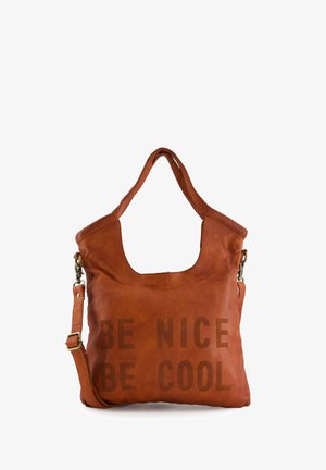 Bruine leren tote bag met een gebogen bovenkant, voorzien van de tekst "WEES VRIENDELIJK WEES COOL" afgedrukt aan de voorkant. Inclusief korte handvatten en een afneembare schouderband.