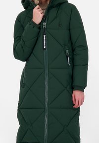 Mörkgrön lång pufferjacka med huva, med ett diamantquiltat mönster, frontdragkedja och logotyp på dragkedjan.