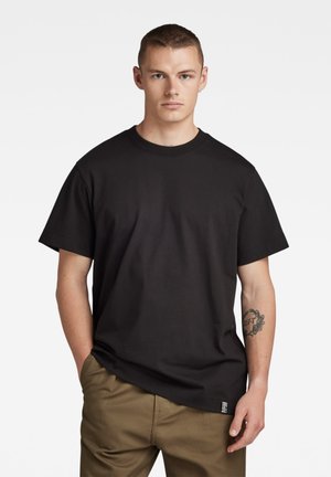 T-shirt in cotone nero con maniche corte e scollatura rotonda; presenta una vestibilità morbida e un piccolo etichetta con il brand vicino all'orlo.