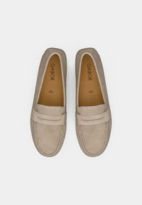 Γκρι σουέντ μοκασίνια με επίπεδη σόλα, με ραμμένη ραφή και ένα μικρό διακοσμητικό λουράκι πάνω από την καμάρα του ποδιού. Το όνομα της μάρκας είναι ορατό στο εσωτερικό.