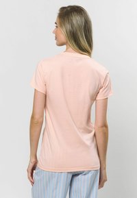 Svetloružové priliehavé tričko, krátke rukávy, hladká textúra. Pohľad zozadu zobrazuje zaoblený výstrih a jemné detaily šitia.