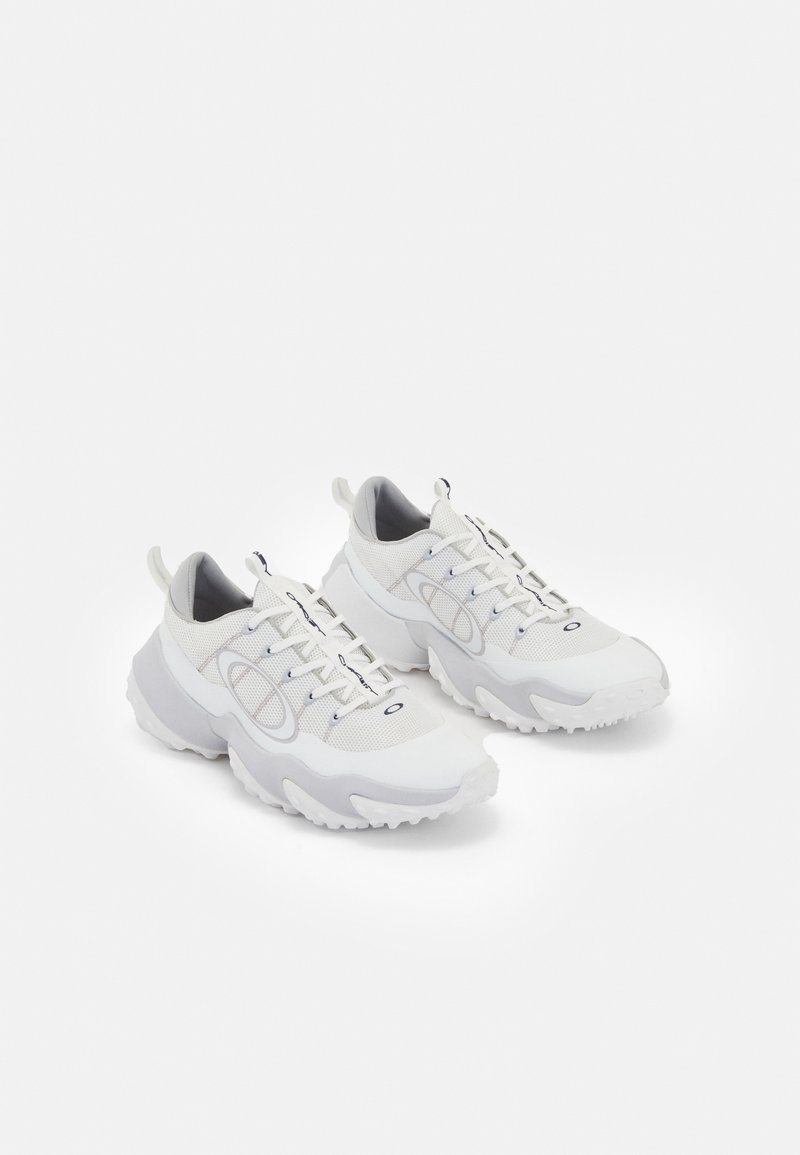 Weiße Sportschuhe mit einem Obermaterial aus Netzgewebe, grauen Akzenten, einer strukturierten Gummisohle und Zuglaschen an der Ferse; verfügt über ein Schnürdesign.