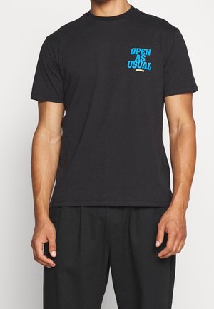 Camiseta de algodón negra con el gráfico "ABIERTO COMO DE COSTUMBRE" en azul en el pecho. Diseño de manga corta y cuello redondo, ajuste relajado.