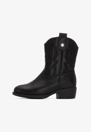 Bota de vaquero de cuero negro con un tacón bajo y cuadrado, costuras en zigzag en el eje y una tira de agarre en la parte trasera. Acentos de herrajes plateados.