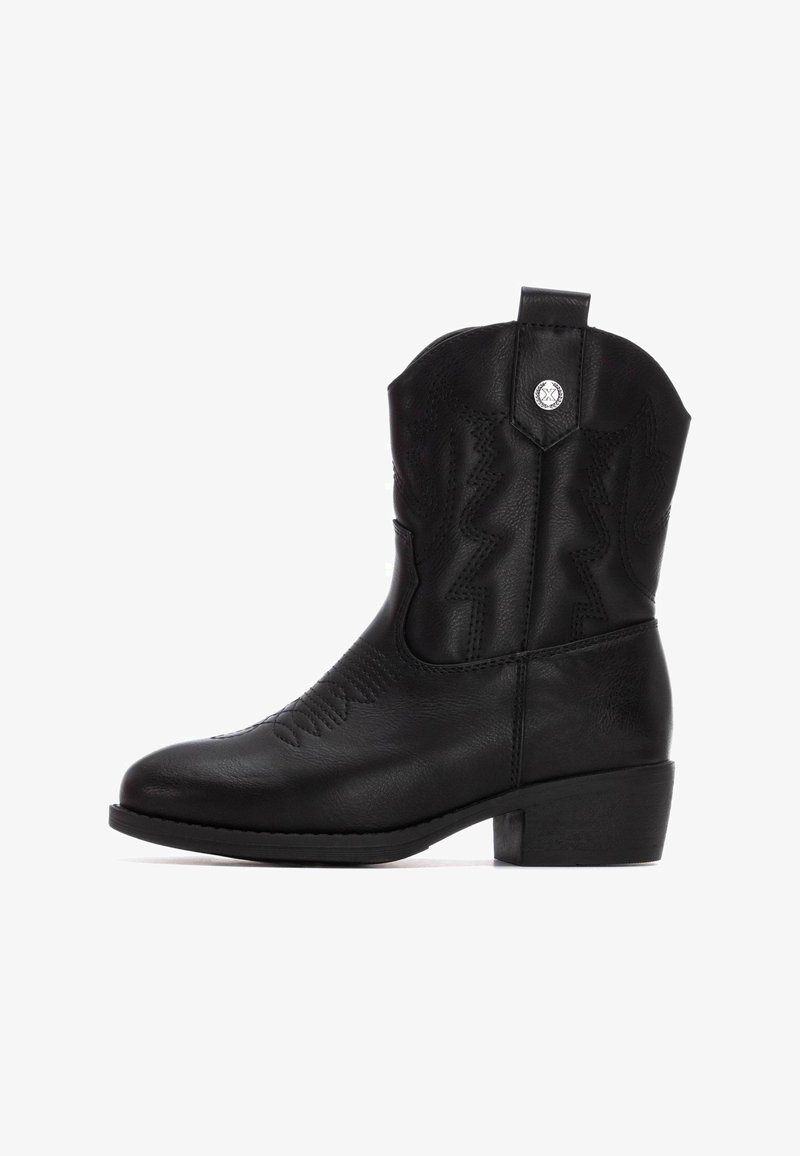 Bota de vaquero de cuero negro con un tacón bajo y cuadrado, costuras en zigzag en el eje y una tira de agarre en la parte trasera. Acentos de herrajes plateados.