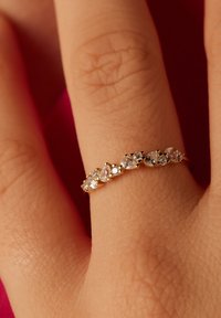 Bague en or ornée de plusieurs cristaux en forme de poire sertis de griffes, affichant une finition lisse et polie et un éclat clair contre la peau.