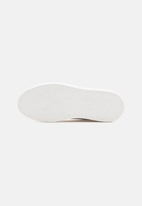 Semelle de sneaker blanche avec un motif texturé en chevrons. Comprend un logo embossé et une surface en caoutchouc lisse et plate pour une meilleure adhérence.