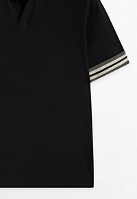 T-shirt noir à manches courtes et en V, avec un ourlet et des manches retroussées, présentant des rayures horizontales blanches et vert foncé.