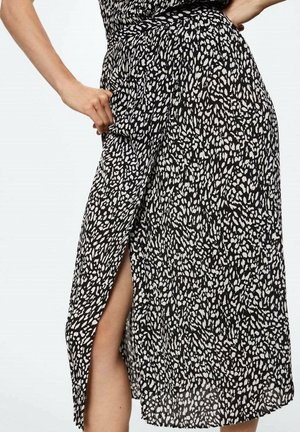 Jupe portefeuille imprimée en noir et blanc avec une fente sur le côté, fabriquée en tissu léger, présentant un motif texturé et une taille définie.