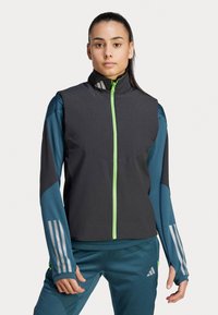 Sportjack met ritssluiting in een zwart en teal ontwerp, met een gestructureerde stof, opvallende verticale lijnen en een felgroene ritsaccent.