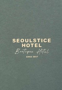 Text in beige on a textured green background: "SEOULSTICE HOTEL Boutique Hotel Since 2017." Simple and modern design.