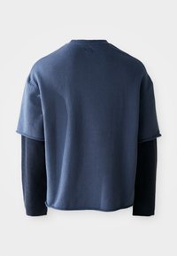 Dunkelblaues Langarmshirt mit strukturiertem Körper und einfarbigen Ärmeln. Mit Rundhalsausschnitt und Oberkörperlänge, die dezente Nahtdetails zeigt.