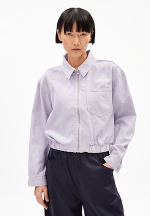 Veste en denim lavande cropped avec un col, fermeture éclair à l'avant et une poche poitrine. Taille élastique et manches longues. Texture lisse.