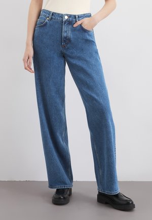 Jasnoniebieskie dżinsy o wysokim stanju z szerokimi nogawkami, wyposażone w przednie kieszenie, szlufki na pasek i zapięcie na guzik.