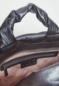 Borsa a mano in pelle marrone con un manico imbottito e testurizzato. Presenta una tasca con zip e un rivestimento interno con un motivo a logo ripetuto in rosa chiaro.