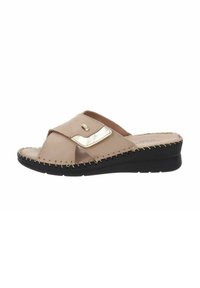 Beige leren slip-on sandaal met een kruisbandontwerp, metalen accent, gestikte details en een lage zwarte rubberen zool.