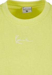 Lime spalvos medvilninė marškinėliai su apvaliu iškirpimu ir baltu siuvinėjimu logotipu krūtinėje. Dydis nurodytas kaip M.