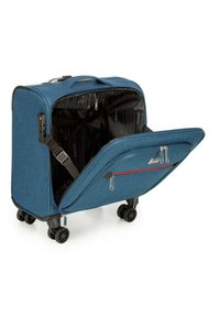 Valise en tissu bleu avec une coque rigide, quatre roues, un compartiment principal ouvert et une poche frontale zippée avec des accents rouges.