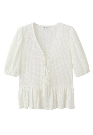 Blouse blanche à texture avec manches bouffantes courtes, col en V, trois fermetures à nouer à l'avant et ourlet à volants.