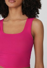 Top corto aderente in tessuto a coste di un vivace rosa. Scollo quadrato e spalline larghe. Fresco al tatto con un pattern a coste uniforme.