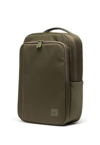 Maslinasto zeleni ruksak pravokutnog oblika, izrađen od čvrstog materijala, s dva odvojena pretinca sa patentnim zatvaračem i teksturiranim bočnim džepom.