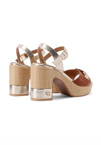 Sandali platform in pelle marrone con accenti metallici dorati e texture intrecciata. Tacco spesso con base dorata lucida e cinturini alla caviglia regolabili.