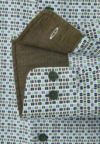 Shirtmanchet met groenachtige-bruzze binnenzijde, witte stof met een abstract vierkant patroon in blauw, groen en zwart, en groene knopen.