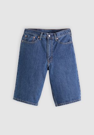 Blå denimshorts med frontknapp, glidelås, beltestropper og femlomme-design på en lys grå bakgrunn.
