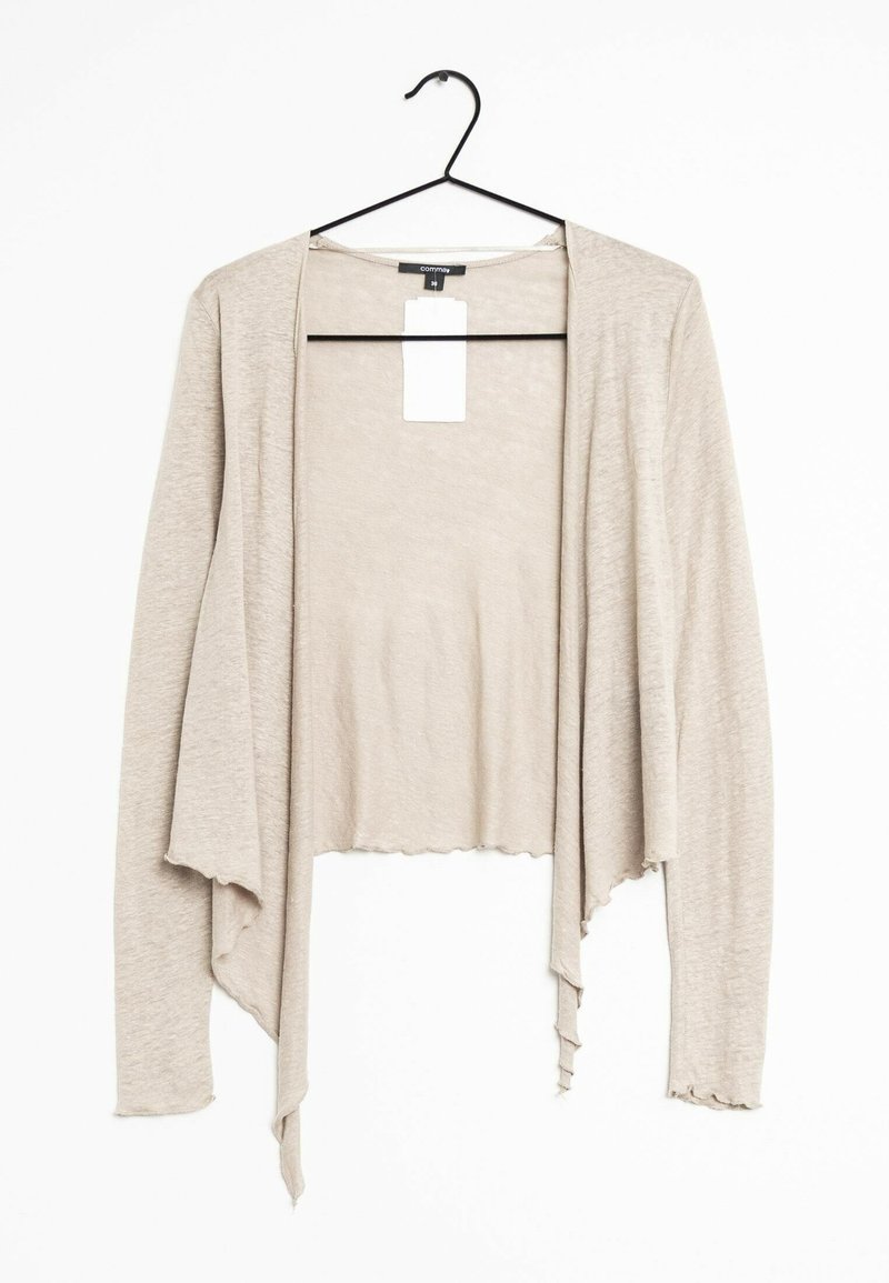 Cardigan beige léger à manches longues avec ouverture devant, suspendu à un cintre noir avec une étiquette blanche de prix attachée au col.