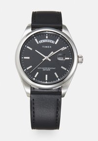 Montre Timex noire avec un boîtier en acier inoxydable, un cadran noir, des marqueurs d'heure argentés, une fenêtre de date et un bracelet en cuir noir. Étanche jusqu'à 5ATM.