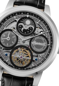 Automatische Uhr mit einem Gehäuse aus silbernem Edelstahl, einem schwarzen Lederarmband und einem komplexen, transparenten Zifferblatt mit zweifacher Zeitanzeige.