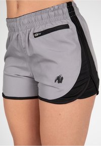 Graue Sportshorts mit schwarzen Akzenten, elastischem Bund, Seitentasche und einem kleinen Gorilla-Logo auf der linken Unterseite.