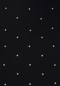 Tissu côtelé noir avec de petites clous ronds argentés espacés régulièrement et disposés en motif régulier.