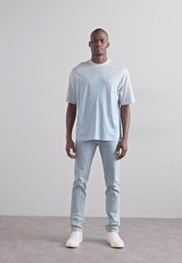 Ανοιχτό μπλε κοντομάνικο μπλουζάκι, μαλακό ύφασμα, άνετη εφαρμογή, συνδυασμένο με ανοιχτόχρωμες skinny τζην και λευκά αθλητικά παπούτσια, κατάλληλο για καθημερινή χρήση.