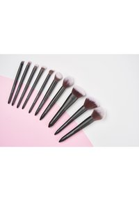Set aus 11 Make-up-Pinseln mit schwarzen Griffen. Verschiedene Borstentypen, sanfte Farbverläufe von dunkel nach hell und glatte, zulaufende Designs.