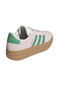 Lichtroze suède sneaker met groene strepen en witte accenten. Rubberen tan zool met gelaagd wigontwerp. Gouden logo detail op de hak.