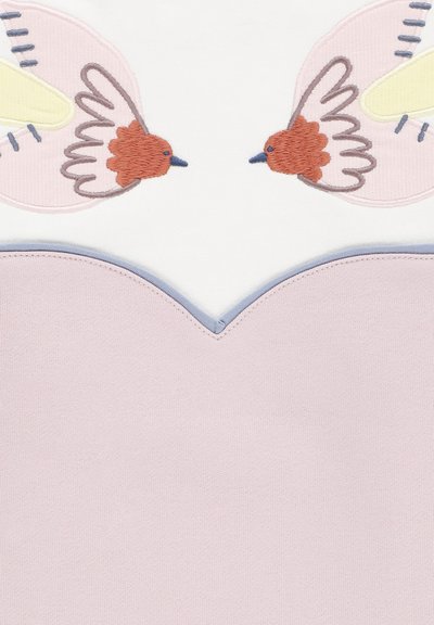 Top ricamato con due uccelli su sfondo bianco; accenti rosa e blu che delineano il collo e l'orlo. Texture del tessuto morbida.