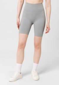 Pantalones cortos de cintura alta de canalé gris, hechos de un material elástico, con un diseño ajustado y longitud a mitad del muslo. Se llevan con zapatillas blancas.