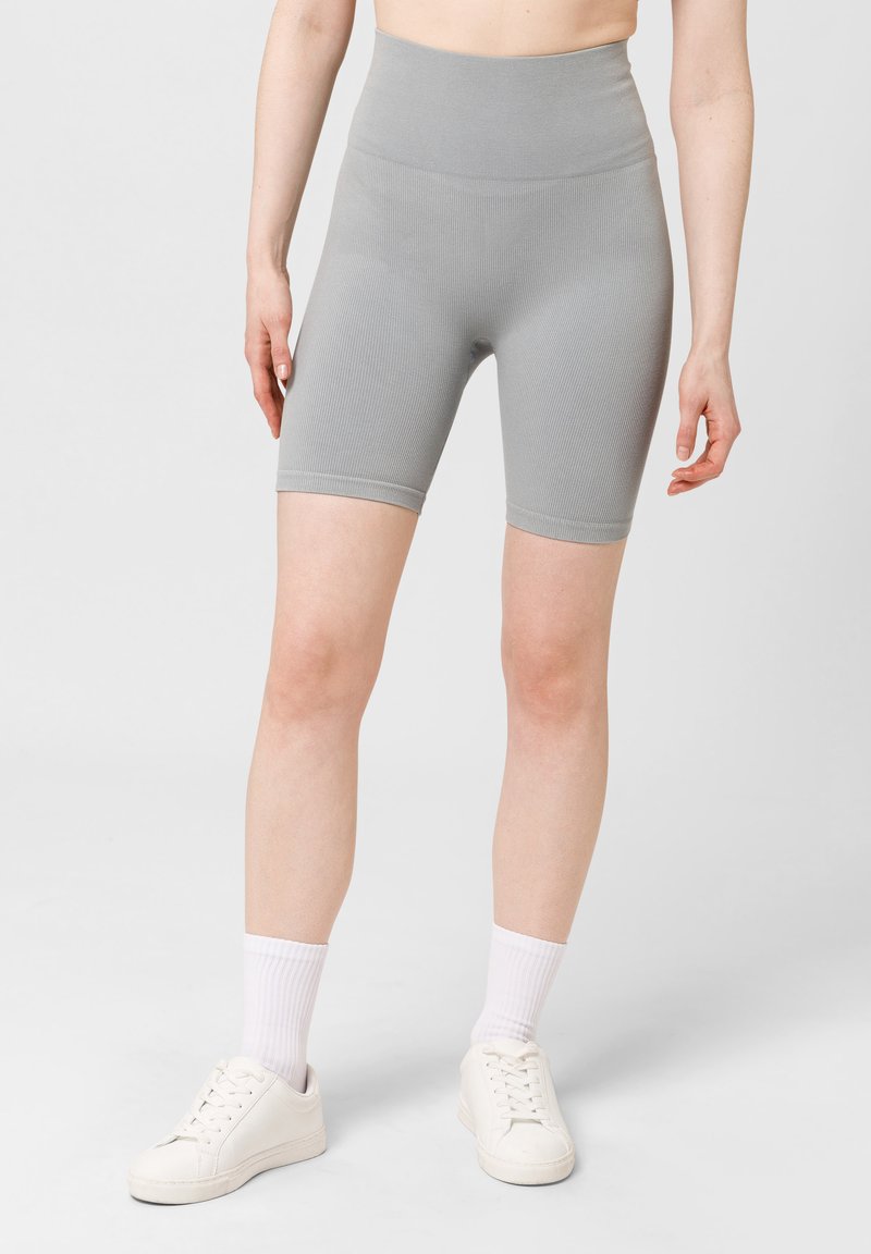 Pantalones cortos de cintura alta de canalé gris, hechos de un material elástico, con un diseño ajustado y longitud a mitad del muslo. Se llevan con zapatillas blancas.