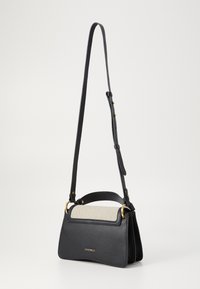 Sac à épaule en cuir noir avec un rabat supérieur en tissu, accents en métal doré et finition texturée, doté d'une bandoulière réglable.